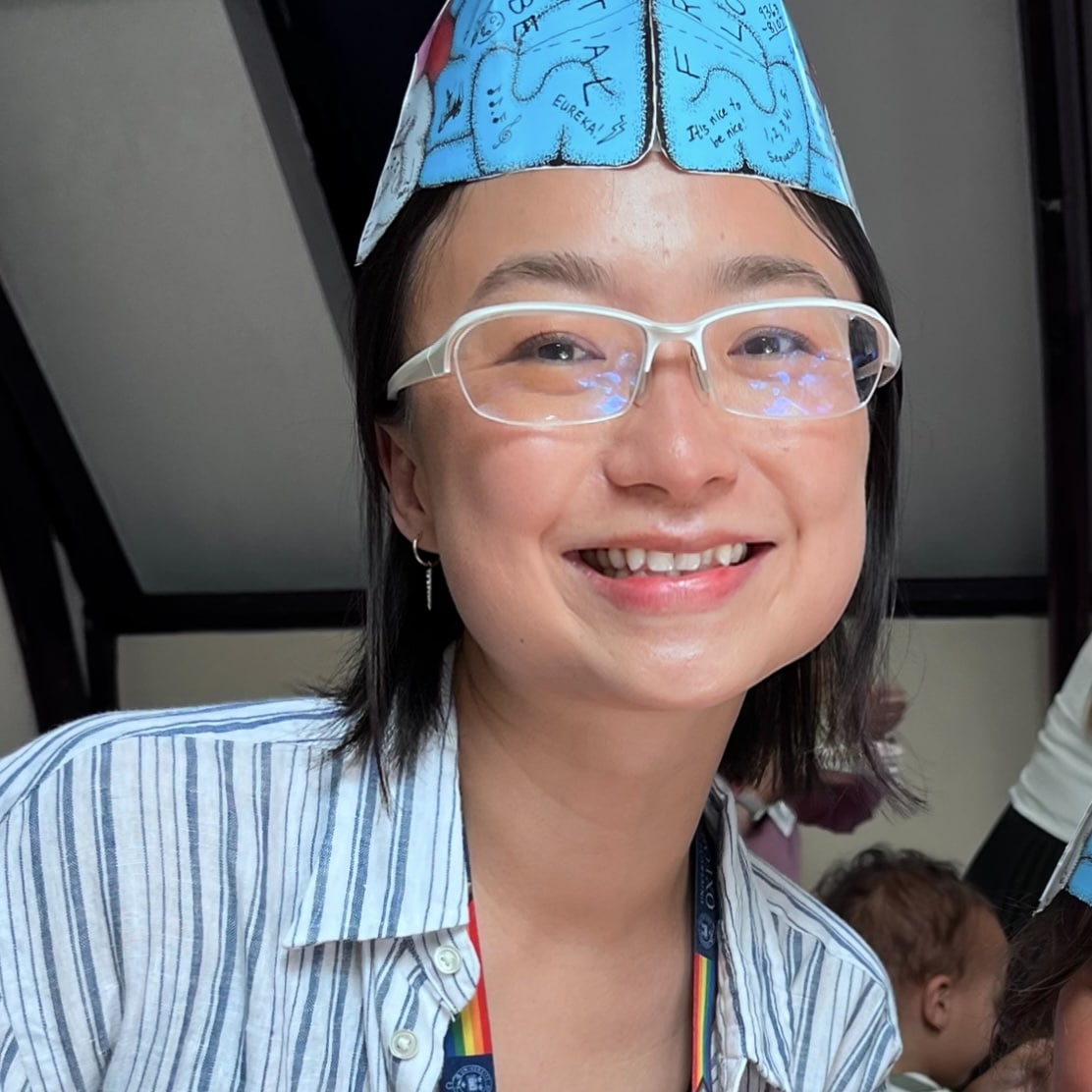 Photo of Lin, wearing glasses and a paper hat